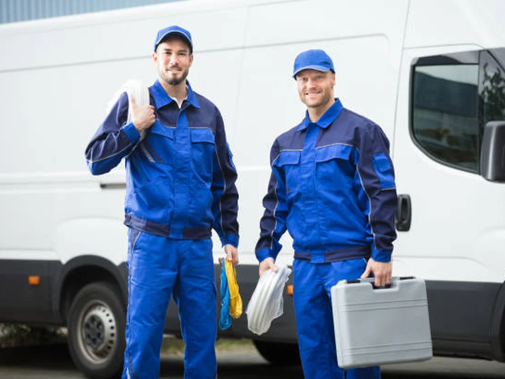 Plumbing technicians standing beside a service van